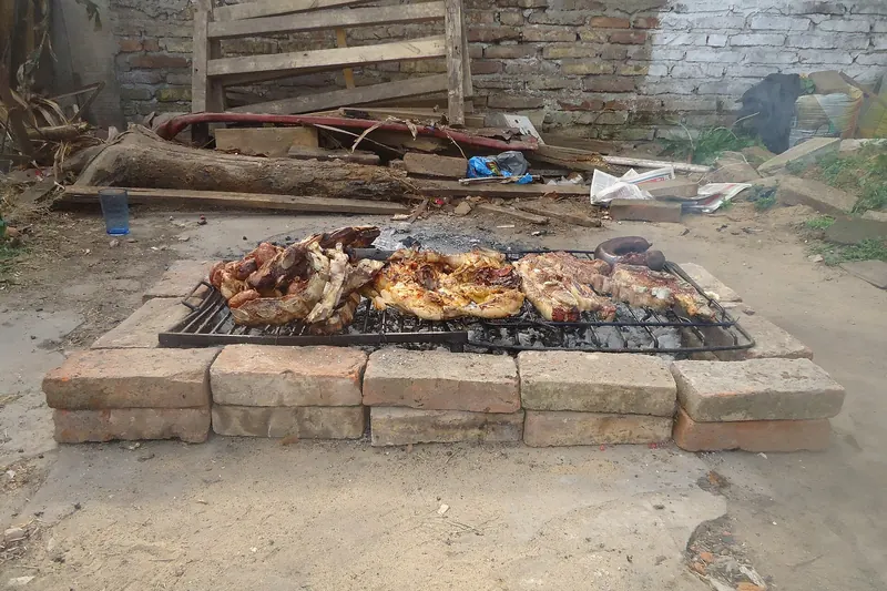 Beef and sausages cooking on an Argentine asado grill over embers