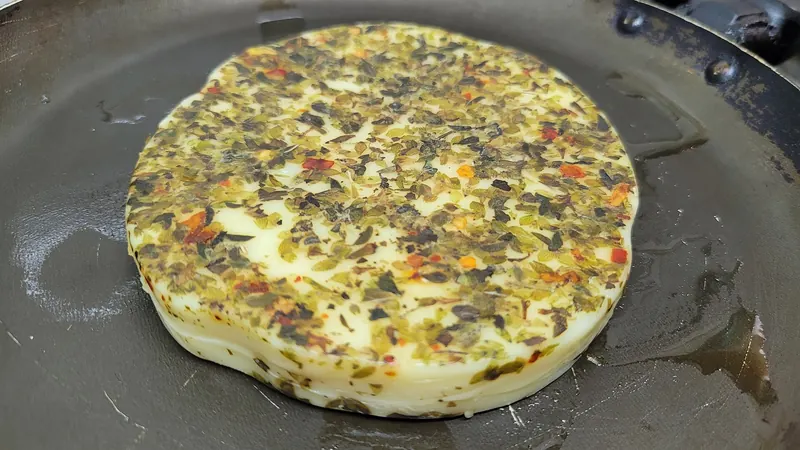 Grilled provoleta cheese with oregano in a small iron dish