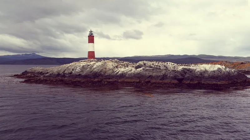 The red-and-white Les Éclaireurs lighthouse on a rock in the Beagle Channel