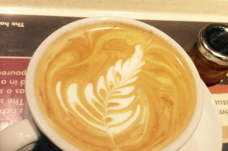 A flat white coffee with a feather pattern in the microfoam