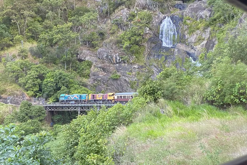 A vintage train of the Kuranda Scenic Railway climbing through rainforest