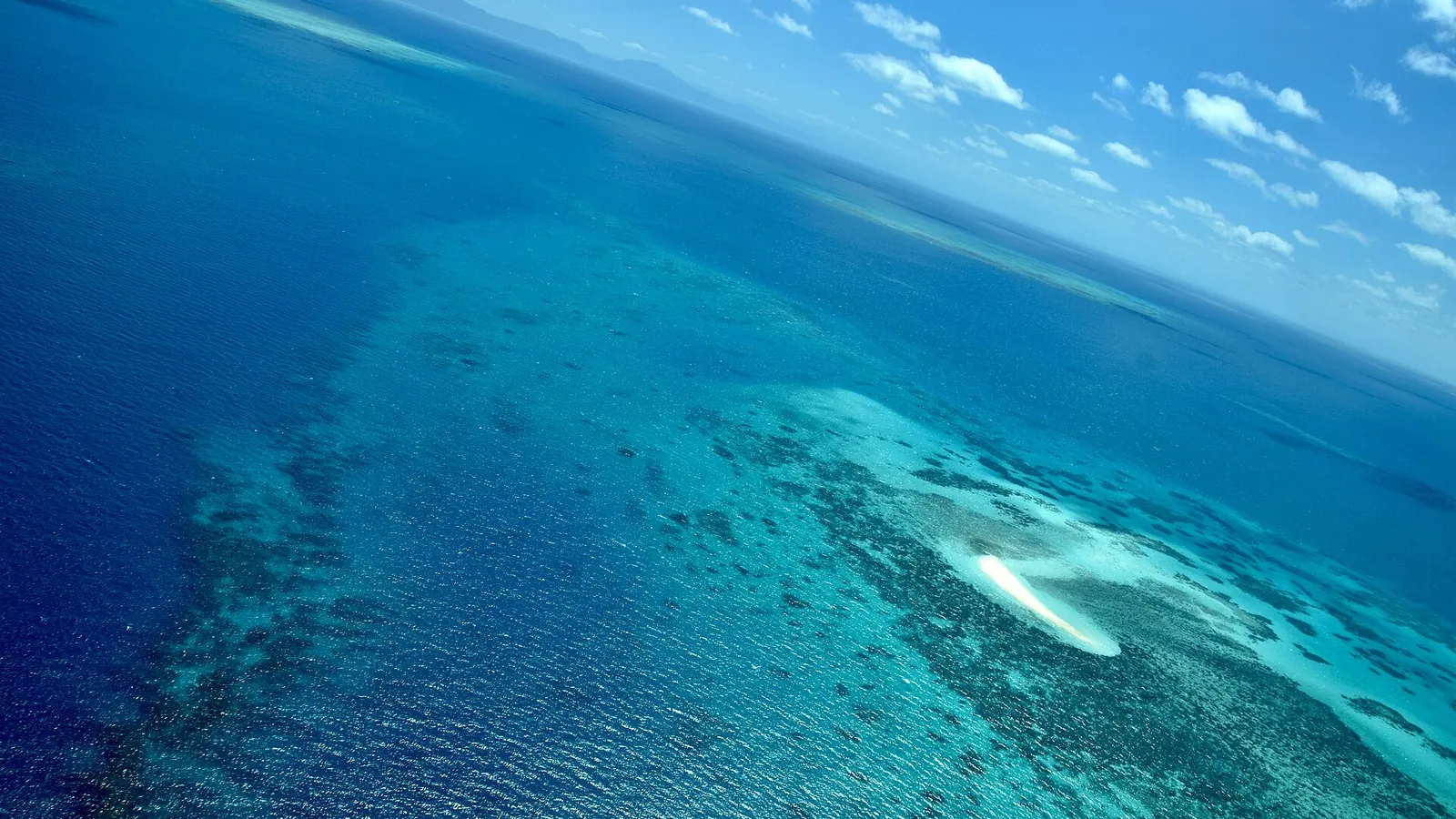 An aerial view of coral reefs and turquoise water on the Great Barrier Reef