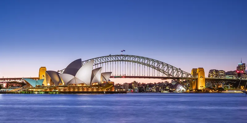 The Sydney Opera House and Harbour Bridge at dusk across the harbour