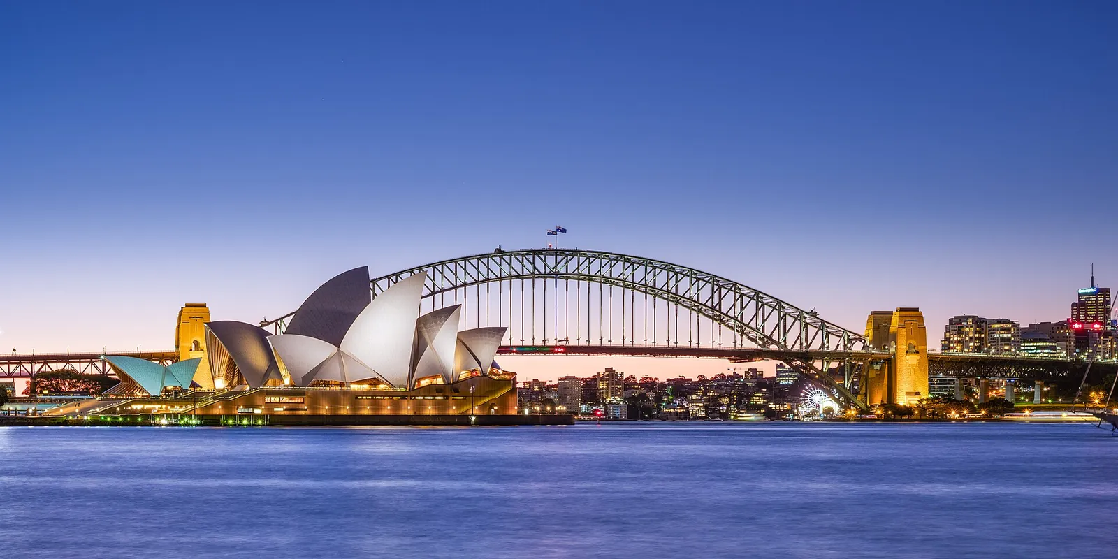The Sydney Opera House and Harbour Bridge at dusk across the harbour