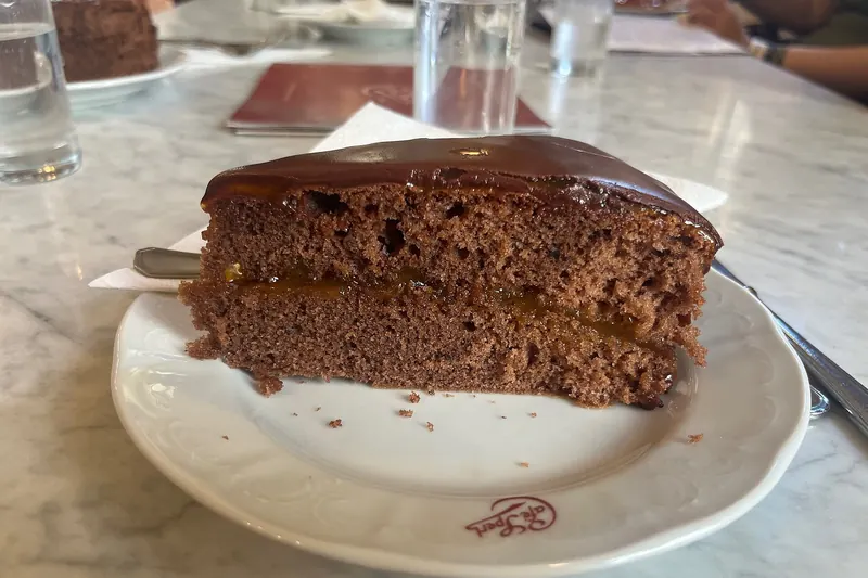 A slice of Sachertorte, Austria's famous chocolate cake, with whipped cream