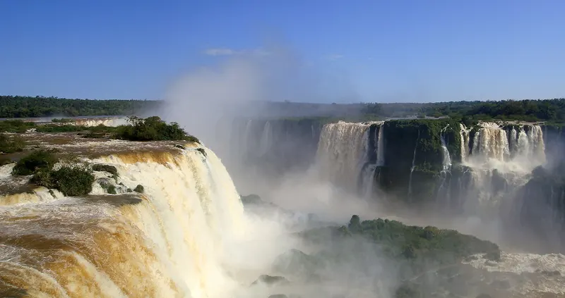 A wide panorama of the Iguazu Falls with many cascades in the rainforest