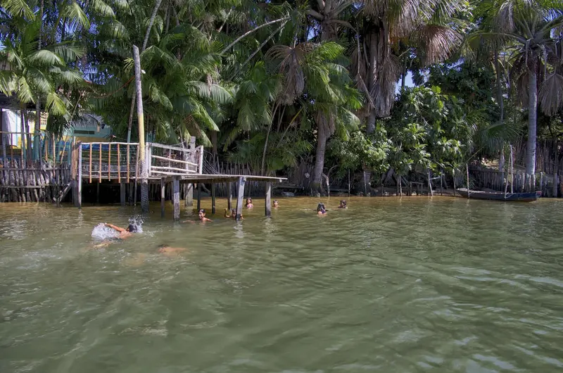 A boat on the Rio Preguiças with dunes and mangroves at Barreirinhas