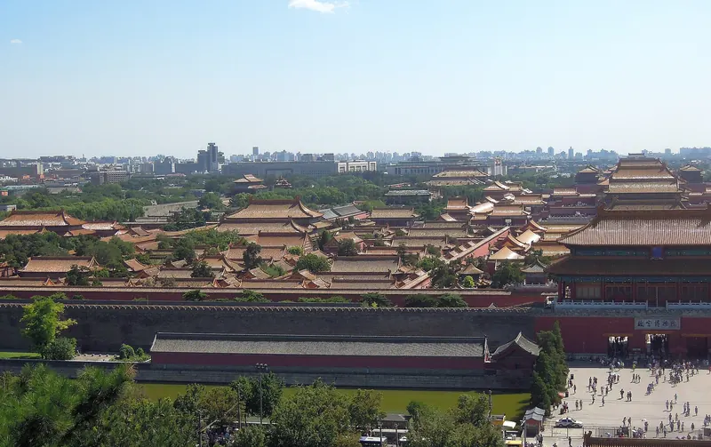 An aerial view over the golden roofs of the Forbidden City with Beijing's skyline behind