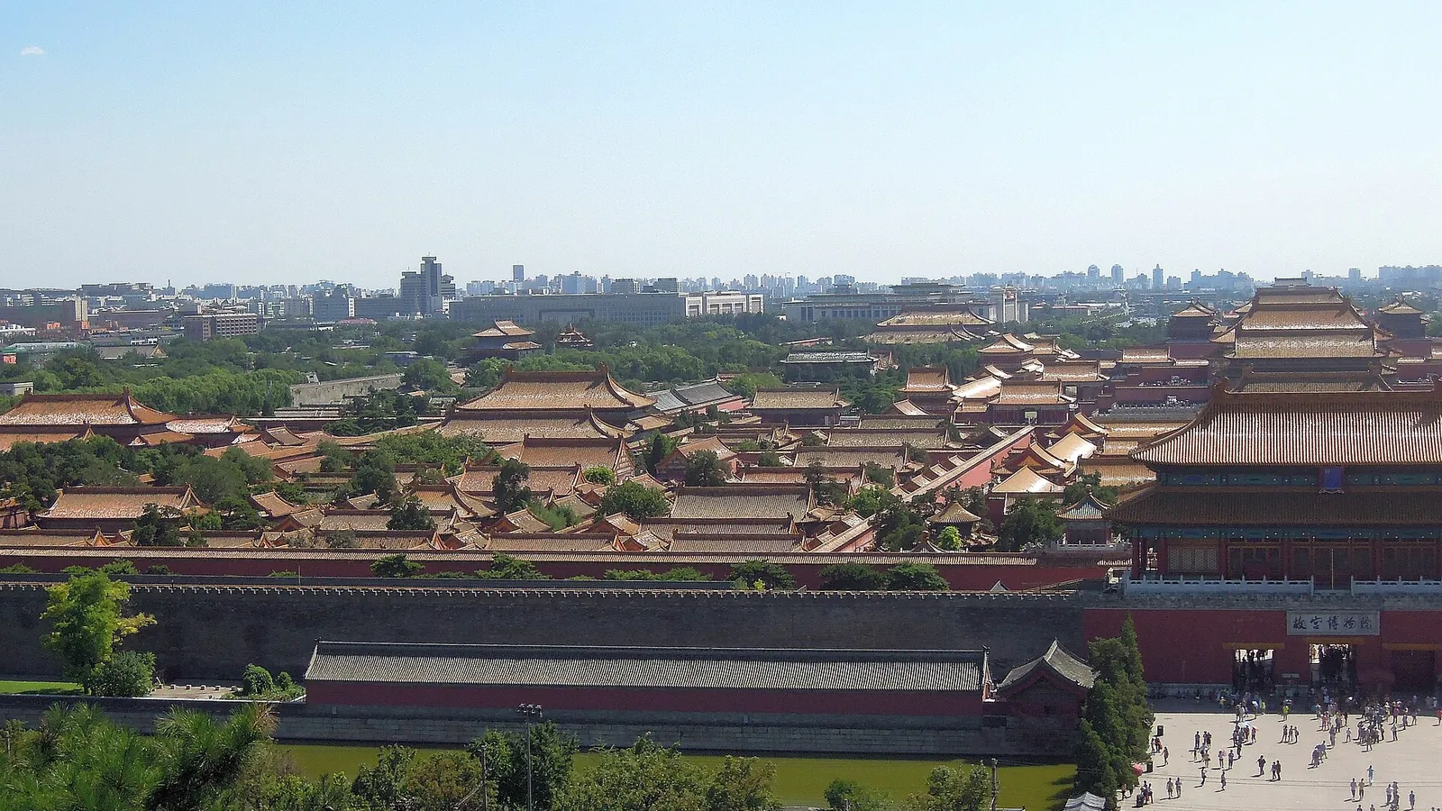 An aerial view over the golden roofs of the Forbidden City with Beijing's skyline behind