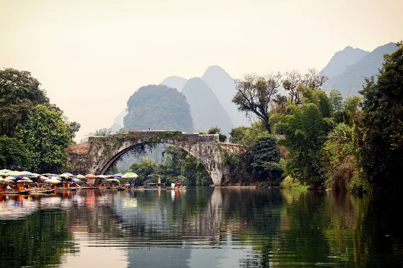 The old stone Yulong Bridge among rice paddies and karst peaks