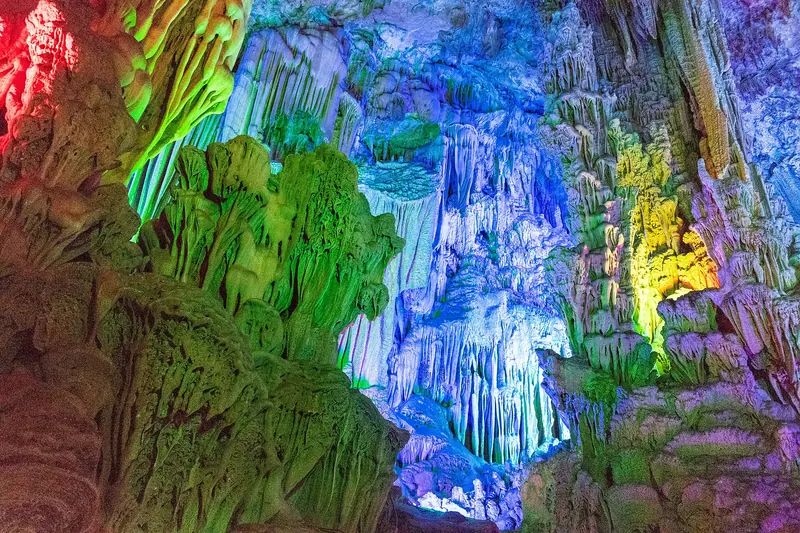 Colourfully lit stalactites and rock formations inside Reed Flute Cave