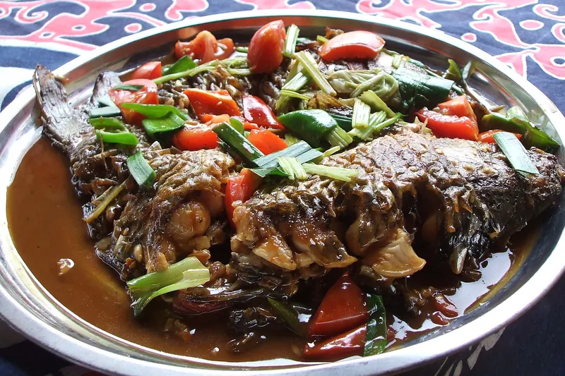 A wok of beer fish braised with tomatoes, chillies and green onions