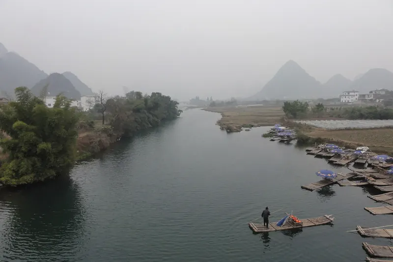 A boatman poling a bamboo raft down the Yulong River