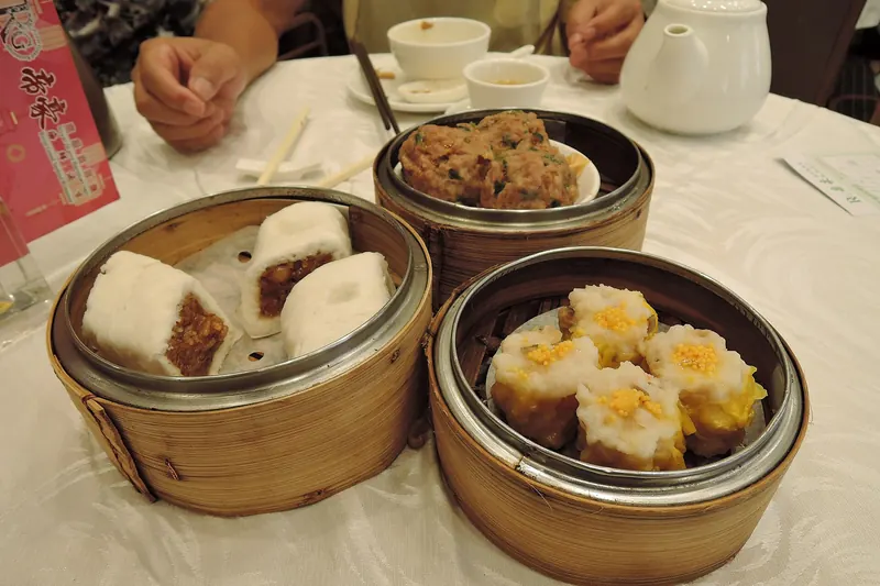 A table set with several dim sum dishes and pots of tea