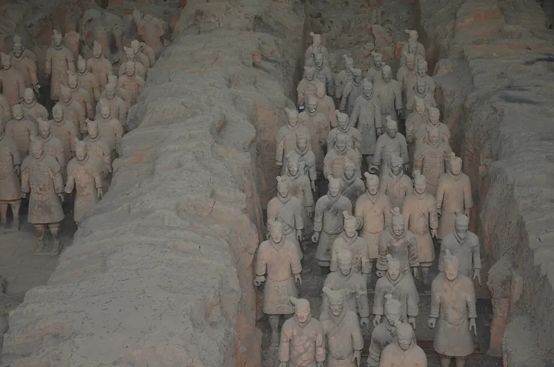 Rows of terracotta warriors standing in formation in their excavation pit
