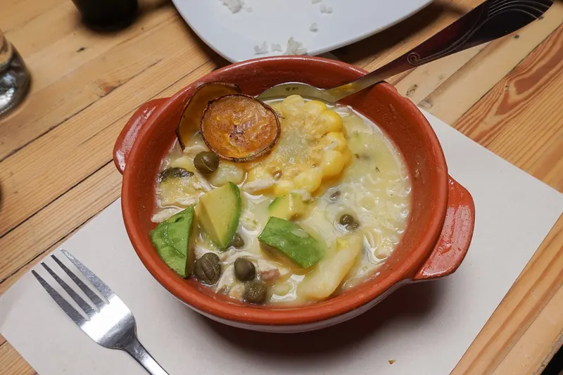 A bowl of ajiaco soup with chicken, potatoes and corn