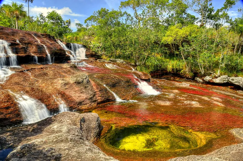 The Manto de la Virgen cascades with red plants beneath clear water