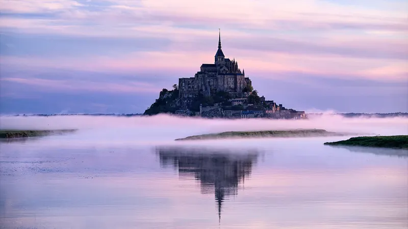 Mont-Saint-Michel across the flats in misty light at sunrise