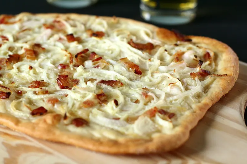 A thin tarte flambée topped with cream, onion and bacon