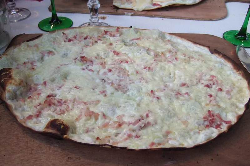 A tarte flambée fresh from the oven on a wooden board