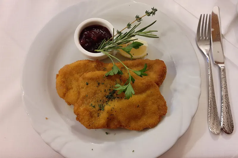 A breaded, pan-fried schnitzel with a lemon wedge
