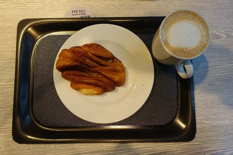 A Franzbrötchen cinnamon pastry with a cup of coffee