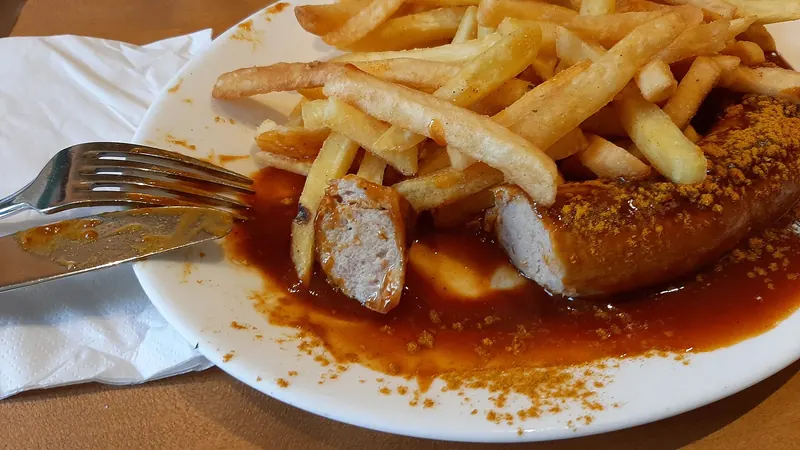 A plate of currywurst with fries
