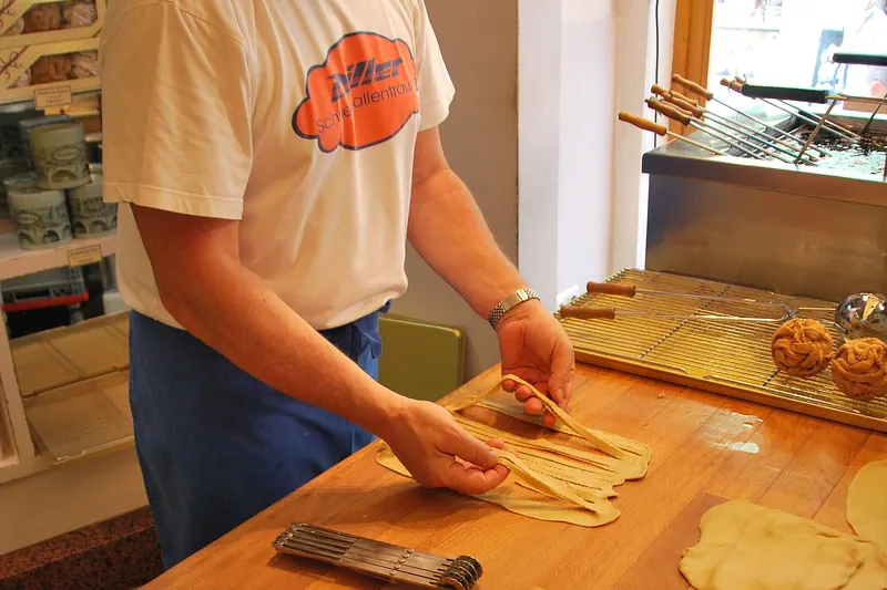 A baker preparing Schneeball pastries in a Rothenburg shop window