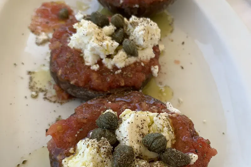 A plate of dakos, a barley rusk topped with tomato and cheese