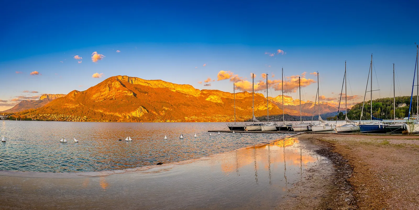 A lake town backed by snow-dusted mountains at golden hour