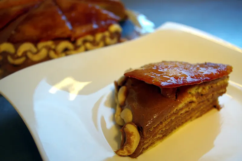 A slice of Dobos torte with layers of sponge and chocolate cream