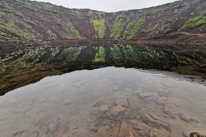 Kerið, a volcanic crater lake with red volcanic rock and a vivid blue-green lake