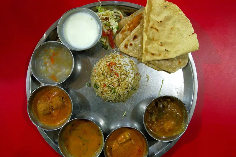 An Indian thali meal with several small dishes served on a steel plate