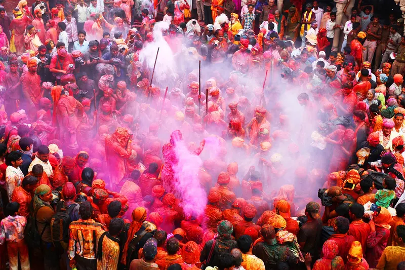Crowds throwing coloured powder at the Holi festival in Barsana