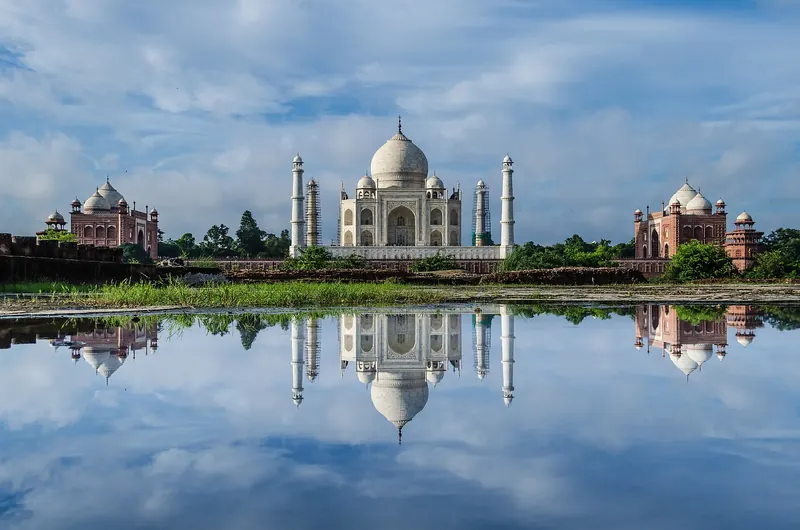 The Taj Mahal reflected in still water at the edge of the Yamuna river