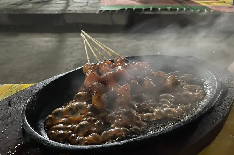 Skewers of Indonesian satay grilling over charcoal