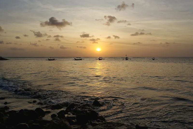 Kuta Beach with surfers in the water at sunset