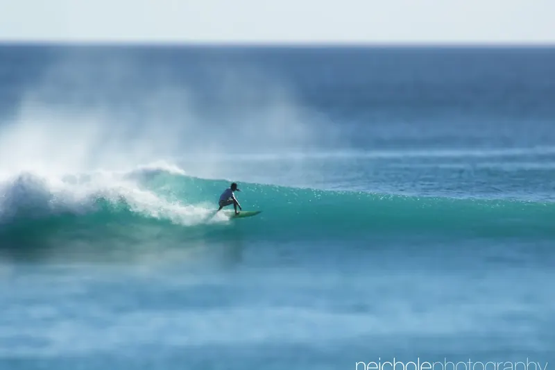A surfer catching a wave off a Bali beach