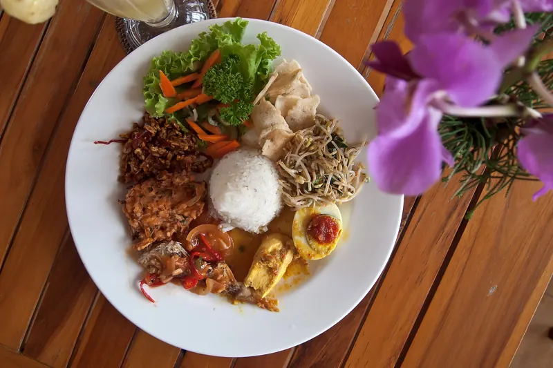 A plate of nasi campur with an assortment of Balinese side dishes