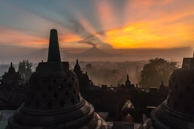 Sunrise over Borobudur temple with a volcano visible in the background