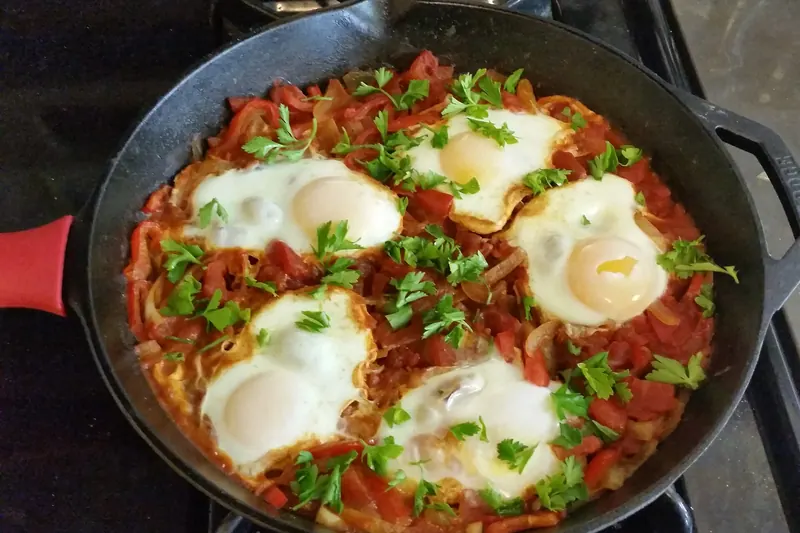 Eggs poached in a spiced tomato and pepper sauce in a pan