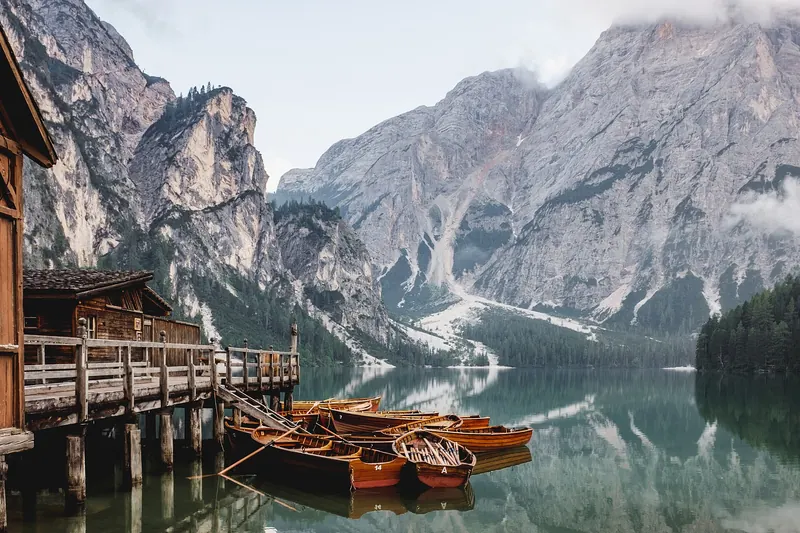 The deep green Lago di Braies beneath a wall of rock, with its wooden boathouse