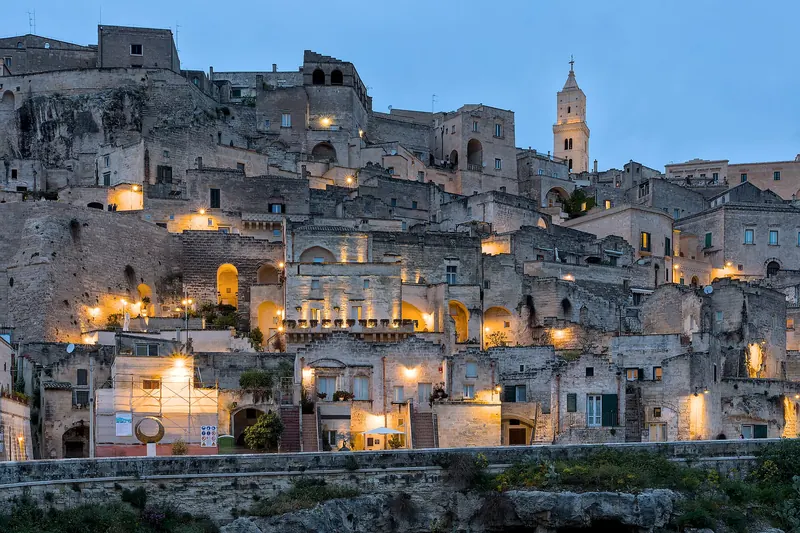 The cave dwellings of Sasso Barisano stacked above the ravine at blue hour
