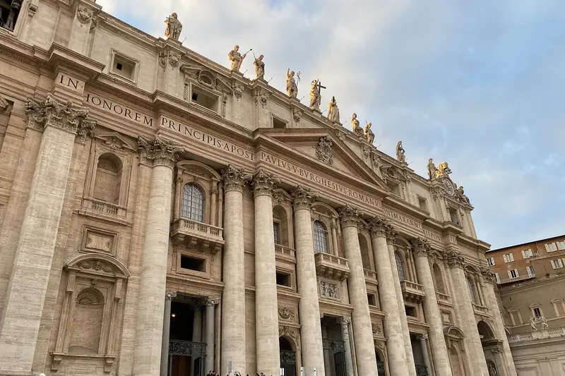 The Baroque facade and dome of St Peter's Basilica above its colonnaded square