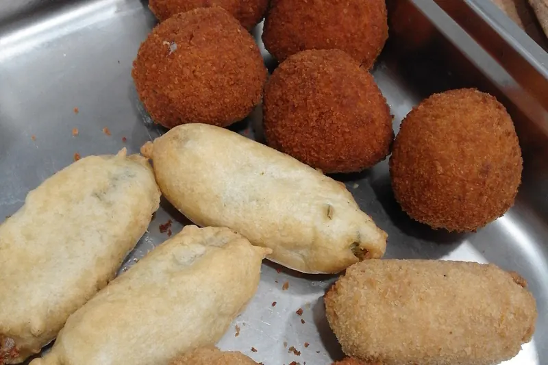 A fried supplì rice ball broken open to show its stretching core of mozzarella