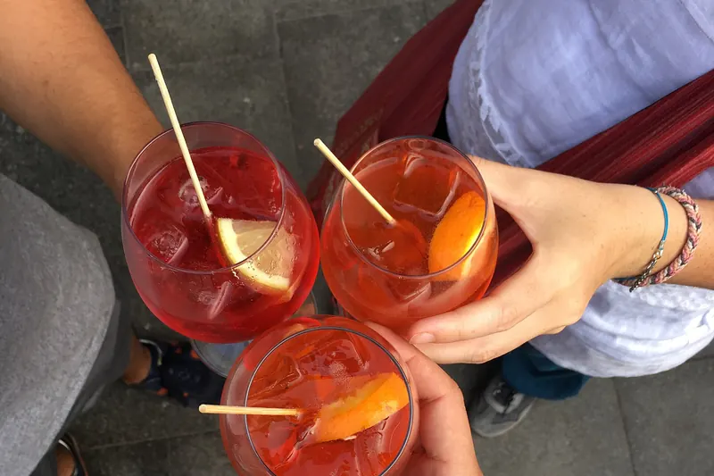 A glass of orange Aperol spritz with ice and a slice