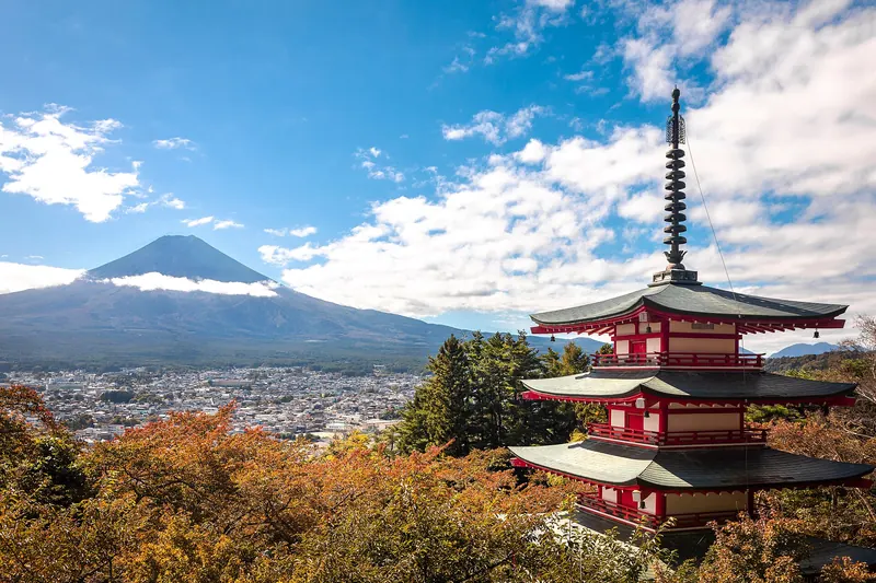 Mount Fuji rising above a traditional pagoda in autumn