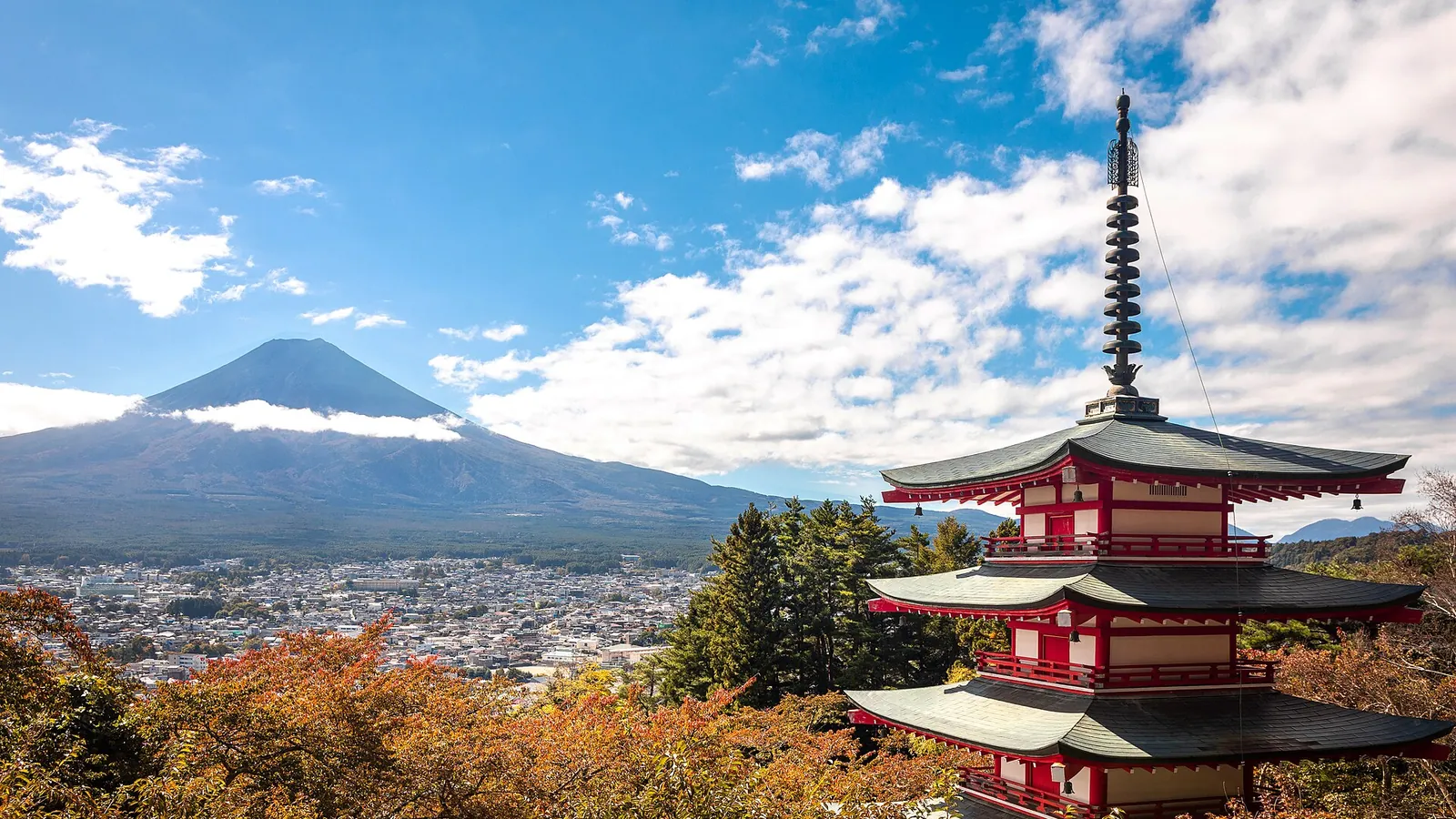 Mount Fuji rising above a traditional pagoda in autumn