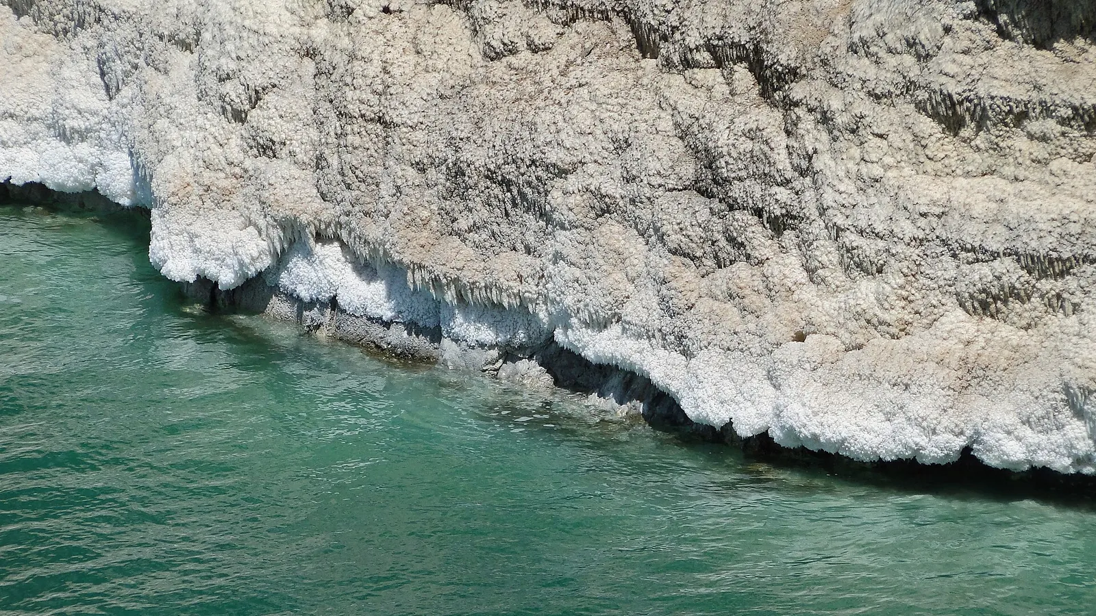 The still blue waters of the Dead Sea on the Jordanian shore