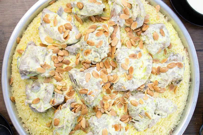 Mansaf served on a large platter of rice and flatbread